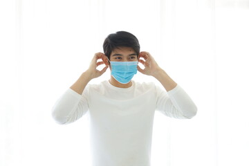 Portrait of young man take off medical mask on white background.