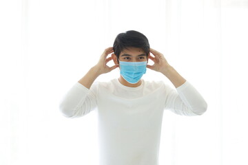 Portrait of a young man wearing a medical mask on white background.