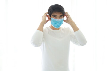 Portrait of a young man wearing a medical mask on white background.