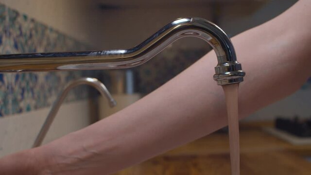 Close up male hand opening water in a faucet after repair. The dirty water comes first, but then it becomes clean. Reparing of plumbing. Housekeeping
