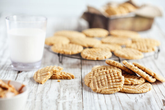 Fresh baked, homemade peanut butter cookies and milk over a white rustic table. Selective focus with blurred background.