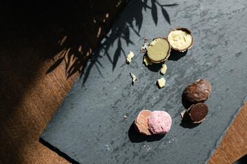three cut up truffle candies on a black plate with green and pink filling