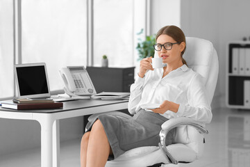 Beautiful secretary drinking coffee in office