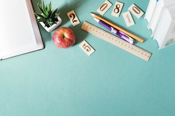 Flat lay photo stationery, books and red apple on a green table. Back to school concept. Mockup, copy space