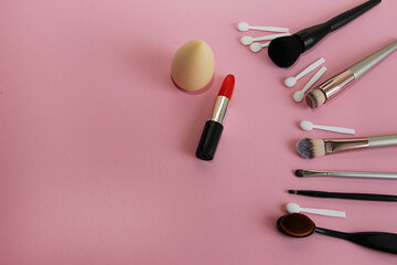 Obraz na płótnie Canvas makeup brushes, red lipstick on pink background
