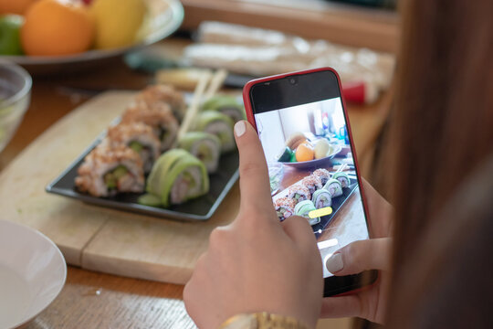 Girl taking a photo of a home made sushi plate with two different sushi rolls
