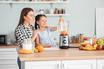 Mother and little daughter making healthy smoothie in kitchen