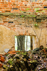 Brick walls of an ancient ruined house. The old facade of a ruined building with Windows. Pile of bricks left from the house. Panoramic photo of an abandoned farmstead.