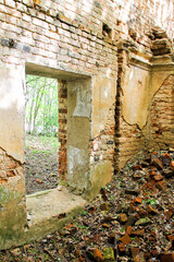 Brick walls of an ancient ruined house. The old facade of a ruined building with Windows. Pile of bricks left from the house. Panoramic photo of an abandoned farmstead.