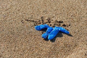 used latex glove thrown on the sand of a beach