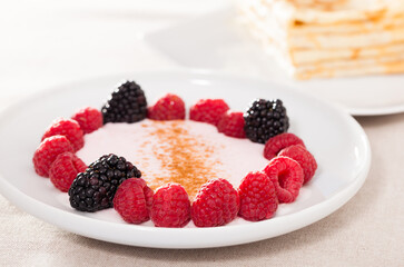 breakfast of raspberries and blackberries with yogurt and pancakes on table