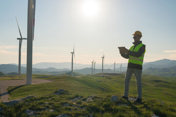 Technician Engineer in Wind Turbine Power Generator Station standing with a tablet in his hands
