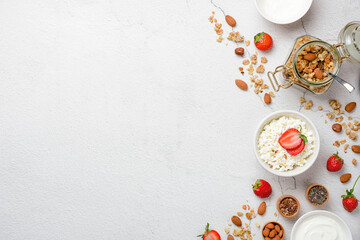 Obraz na płótnie Canvas Cottage cheese strawberries, yogurt with granola, nuts on a white concrete background with copy space. Healthy breakfast concept. Flat lay.