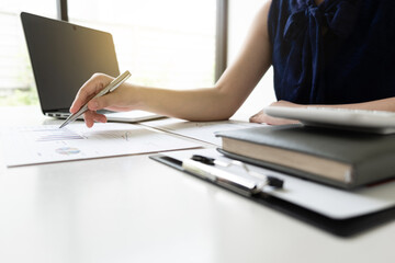 Business women is analyzing marketing strategy from the selling performance graph in the room and work from home.