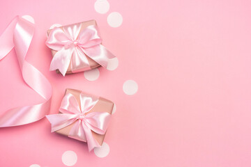 Two gifts or present boxes decorated with confetti and ribbon on pink pastel background. Top view with copy space. Flat lay composition for birthday or wedding. 