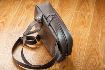 Backpack made of brown genuine leather on a wooden background.