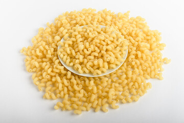 Dried serpentelli Italian pasta in a round bowl ready to be cooked, isolated on a white table, top view or flat lay of healthy food 
