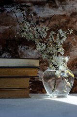a stack of books on the table with a vase of flowers