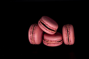 Colored macaroons, French cookies, isolated on a black background. Pink cookies, biscuit