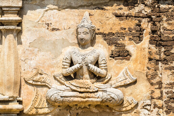 Fototapeta na wymiar Old damaged stucco reliefs carvings of Buddha on the facade of Maha chedi, Wat Chet Yot, Chiang Mai, Thailand