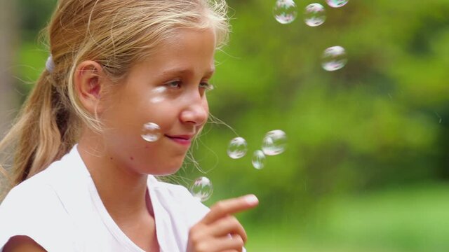 Girl playing with soap bubbles outdoor. Slow motion.
