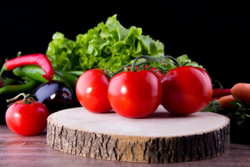 Tomatoes and fresh vegetables on black background wood