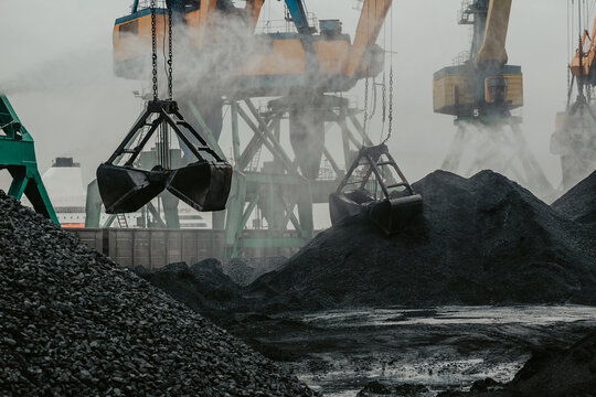 Port Cranes Are Loading Coal Into A Transporting Train.