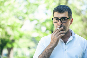 man in glasses smokes on the nature