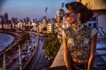 stylish fashionable girl sitting on the roof with a panorama of Marina Drive, Mumbai