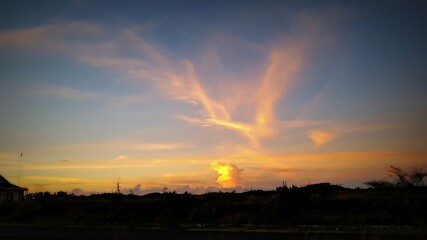 sunset over the city, dramatic yellow oranges clouds in the dark sky