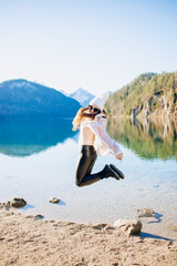 Young stylish girl in a jump on the background of a mountain lake in Bavaria..Winter vacation