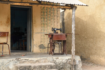 Sewing machine in front of a rustic house on the street in Kpalimé.