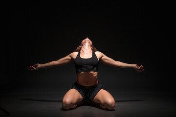 Young girl doing yoga on a black background