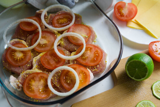 Preparing french meat with tomatoes, cheese, onion, spices and lime 