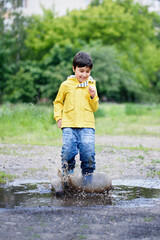 wet child jumping in puddle. Fun on street. Tempering in summer. Splashes, drops of water, outdoor....