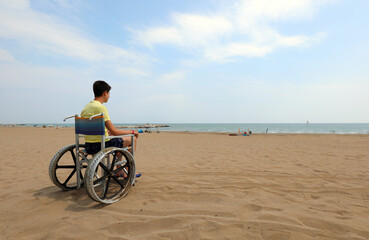 young boy on the wheelchair by the sea