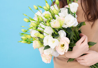 a bouquet of summer flowers in the hands of a girl close-up on a blue background. place for text