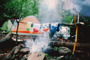 Drying wet socks on the bonfire during camping. Socks drying on fire. Active rest in forest.