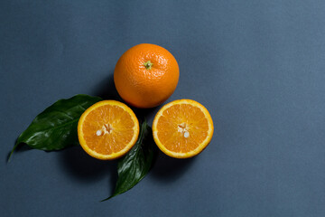 a whole orange and two halves of an orange, and two green leaves