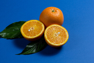 a whole orange and two halves of an orange, and two green leaves