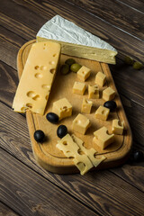 Tasting a cheese dish with olives on an old black wooden table.