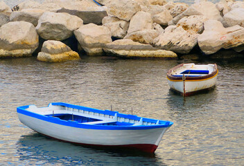 Sea port of city of Naples with small fishing boats on water with colorful sun reflections, Napoli Italy       