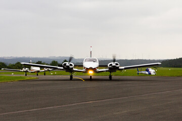 Two twin engine aircraft Piper PA 34 Seneca taxiing at Holzminden-Höxter airport with a wind farm...