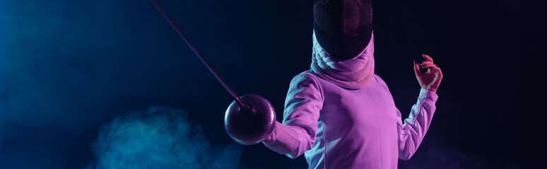 Panoramic crop of swordswoman fencing on black background with smoke and lighting - obrazy, fototapety, plakaty
