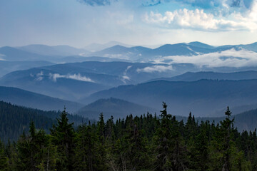 Misty mountain ranges illuminated by the rays of the sun breaking through the cloudy sky