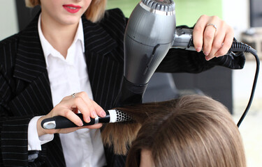 stylist drying woman hair in salon