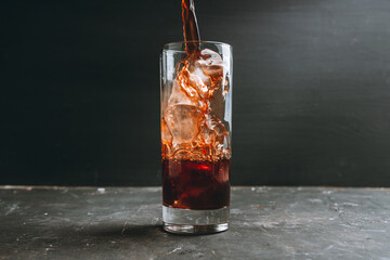Pouring coffee in glass with ice cubes. Selective focus.
