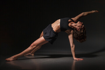 Fototapeta na wymiar Young girl doing yoga on a black background