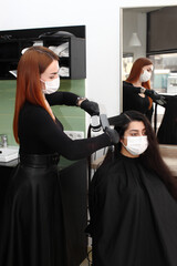 hairdresser in a medical mask works in the salon