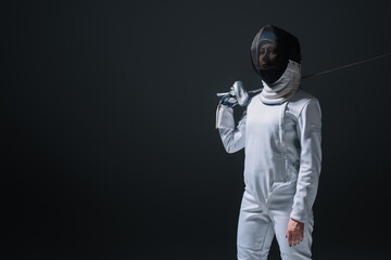 Fencer looking at camera while holding rapier isolated on black